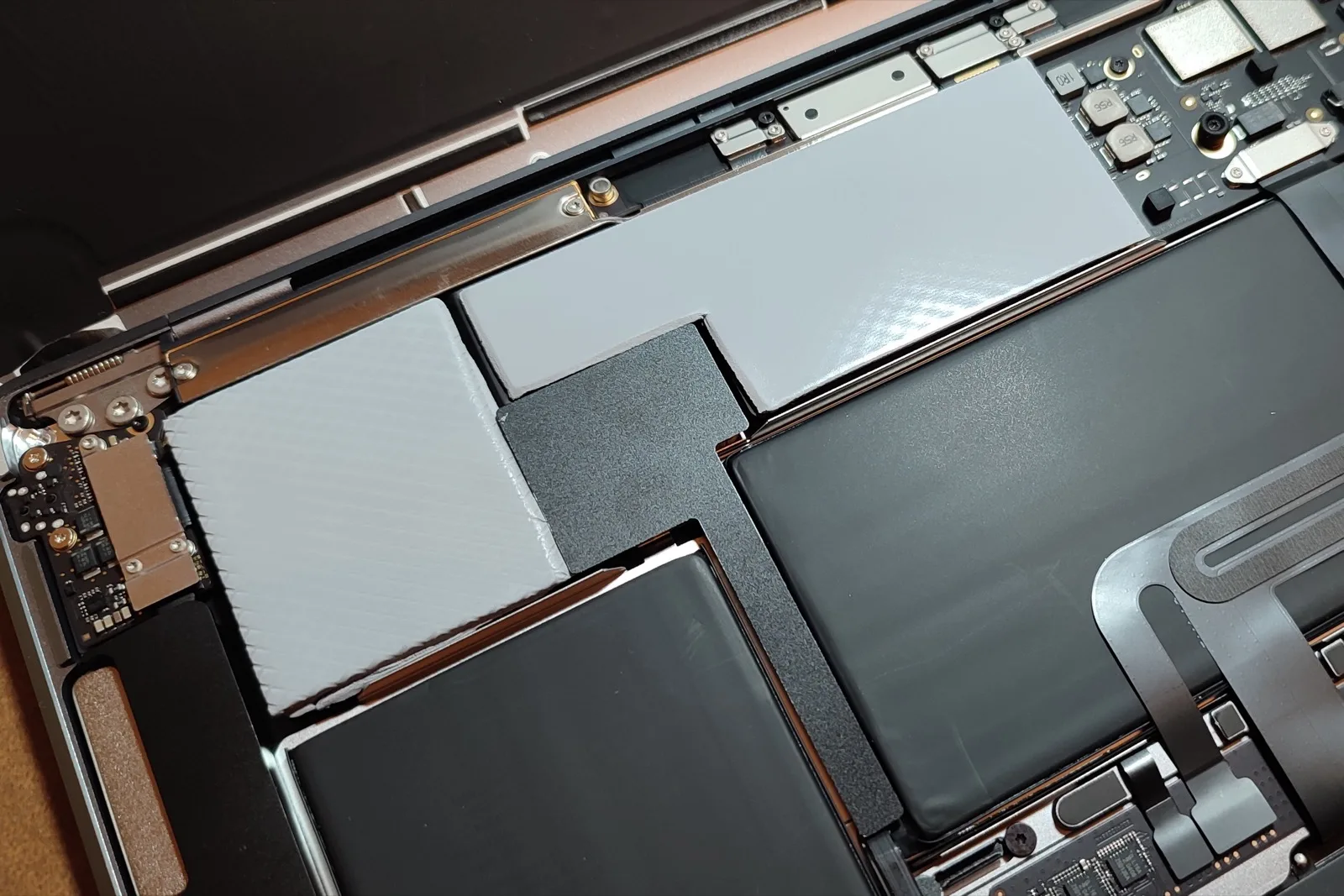 Light-grey silicone thermal gap pads bridging components of different heights inside a disassembled laptop